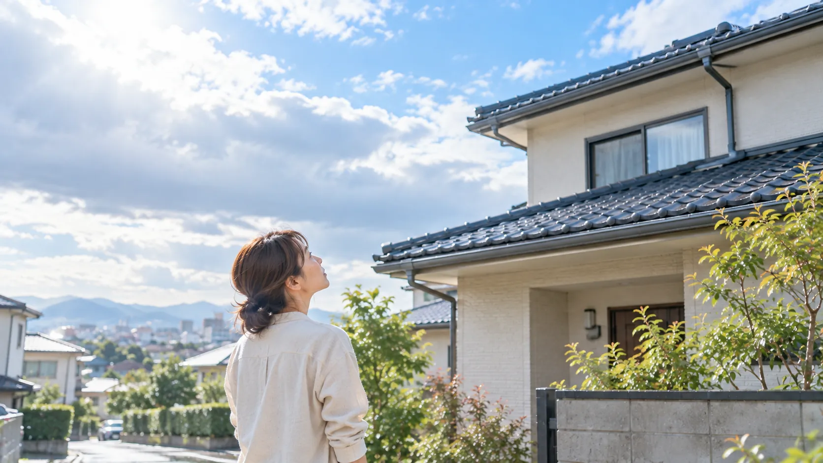 雨上がりの空の下、自宅の屋根を見上げる女性